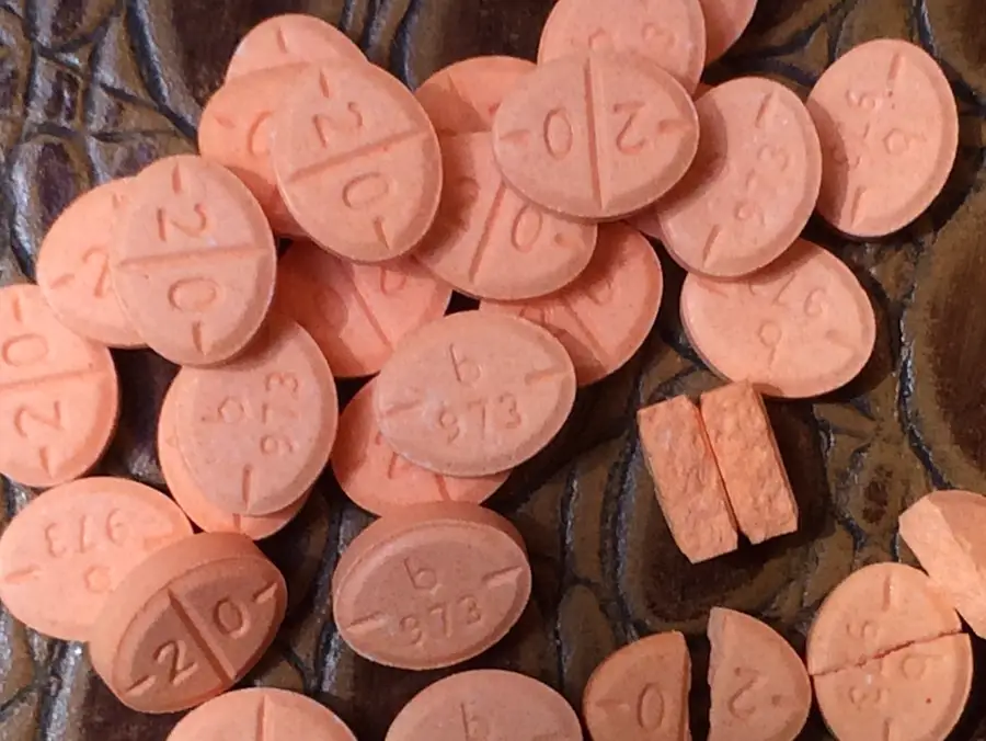 Woman holding Adderall 20mg pills with a California map in the background. https://smithscottpharma.com/