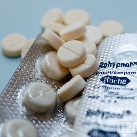 "A close-up of a Rohypnol 2mg pill with a secure online pharmacy website displayed on a laptop screen."